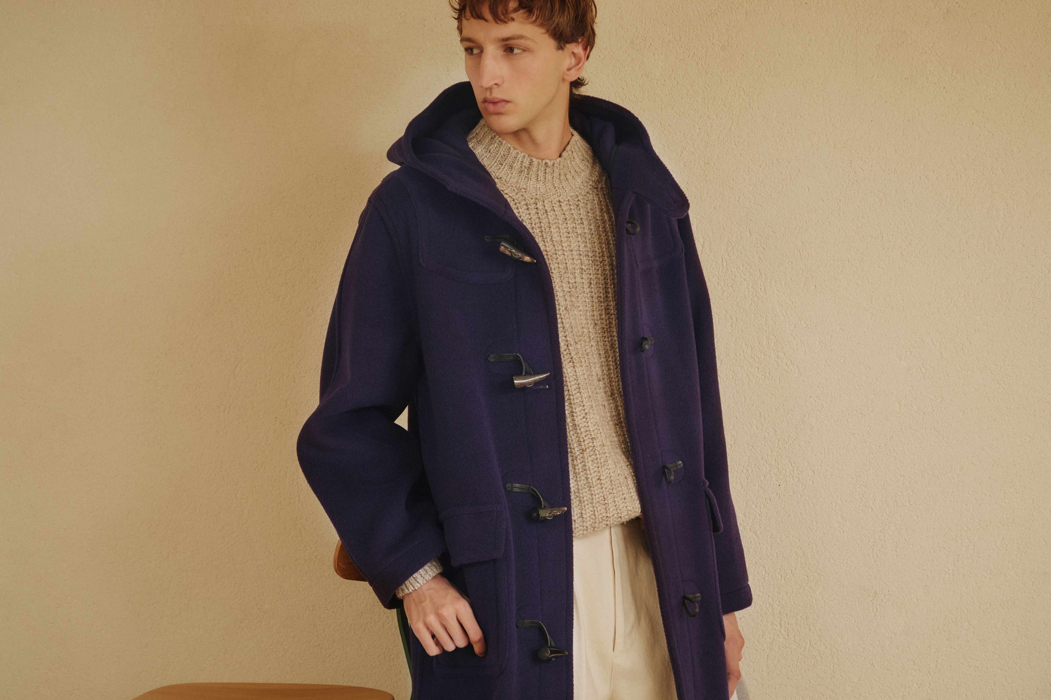 Model wearing a navy GLENMORE duffle coat over a cream knit