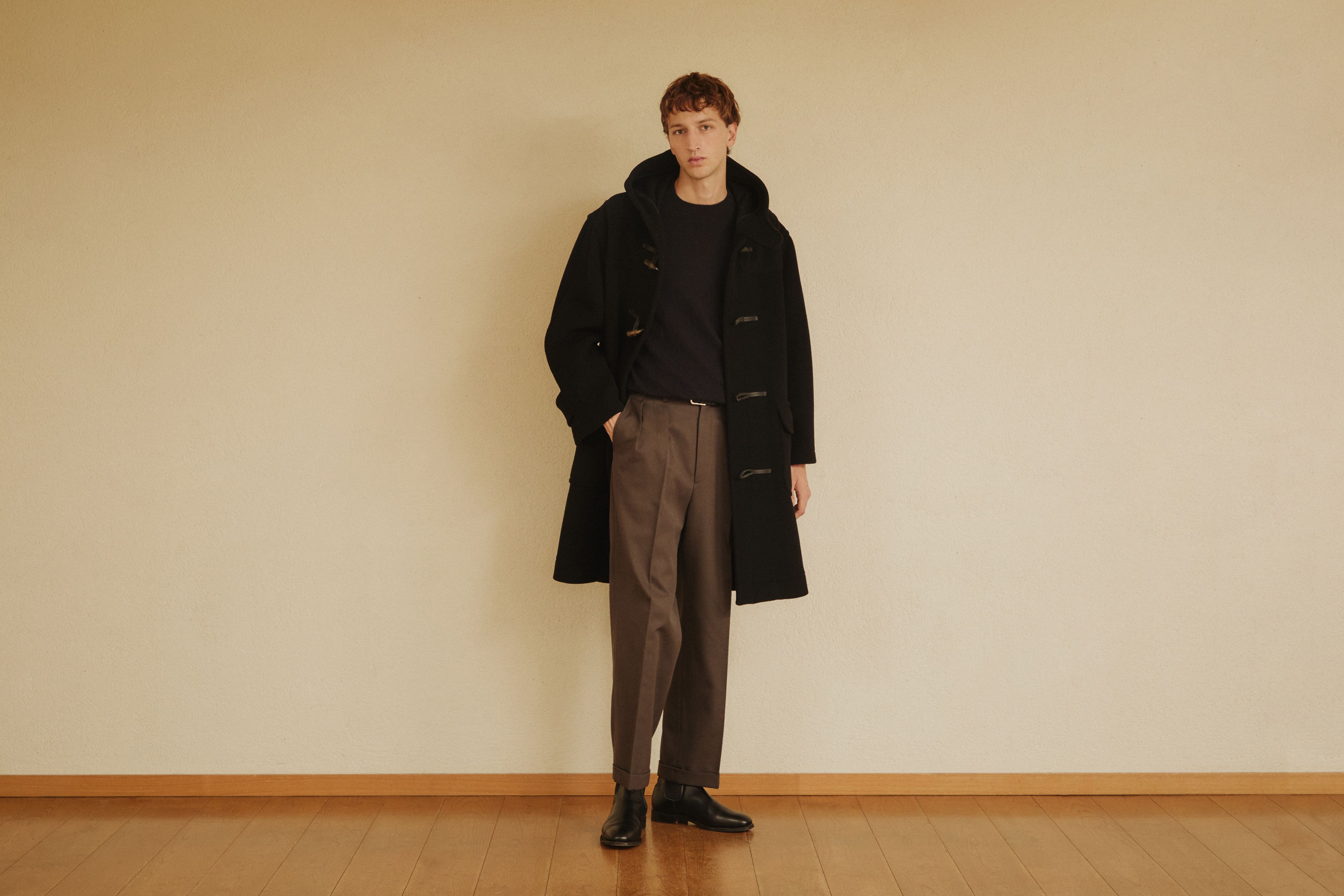 Model wearing a black GLENMORE duffle coat with brown trousers